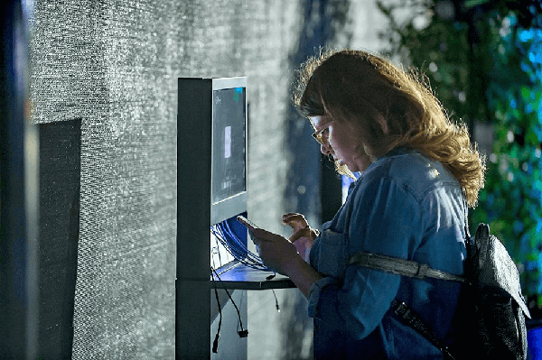 woman using cell phone charging station at night with glasses
