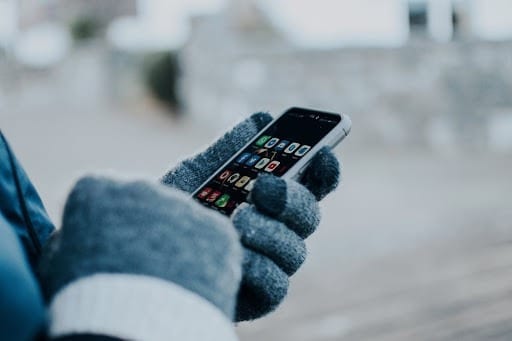 closeup of holding smart phone in the cold wearing gloves