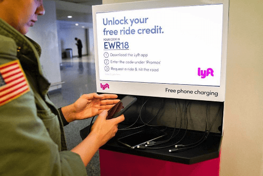 Woman using Lyft cell phone charging station at Newark International Airport (EWR)