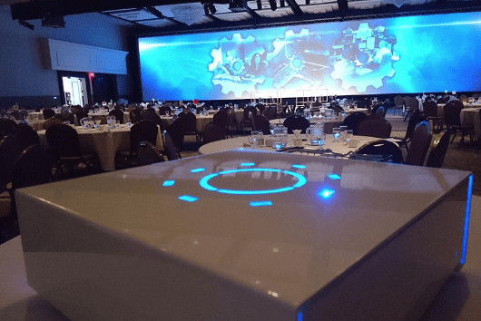 White tabletop PowerBox USB charging station at event conference in ambient lighting with blue LEDs